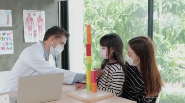 Yüz maskesi takan bir anne hasta kızını çocuk kliniğinin pediatri bölümündeki Asyalı bir erkek doktorla muayeneye getirir. Hastalıkları tedavi etmek ve aile sağlığı konusunda danışmanlık yapmak için..