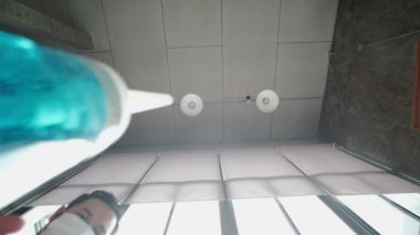 Çatı katının arka planında alçak açılı çekim, yüz maskeli adam alkol jeli şişesini bırak ve aşağı doğru akış. El yıkama, koronavirüs (COVID-19) gibi hastalıkları önler.).