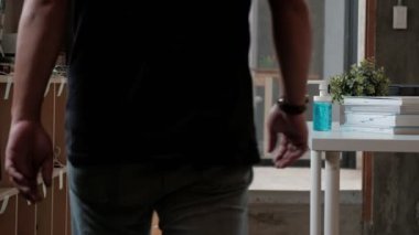 Yakın çekim: Sıradan bir adam, sağlık hijyeni için bir şişe alkol jeli, el dezenfektanı ve Coronavirus (Covid-19) gibi hastalık ve bakterileri evde çalışırken önlemek için baskı yapıyor..