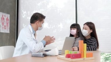 Yüz maskesi takan bir anne hasta kızını çocuk kliniğinin pediatri bölümündeki Asyalı bir erkek doktorla muayeneye getirir. Hastalıkları tedavi etmek ve aile sağlığı konusunda danışmanlık yapmak için..