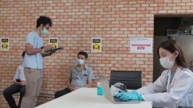 Hemşire, aşılanmış insan kuyruğunu kontrol eder, Coronavirus 'u (COVID-19) sağlık kampanyası için korur. Hastalar, hastalıktan korunmak için oturup, sosyal mesafeyi koruyorlar ve maske takıyorlar..