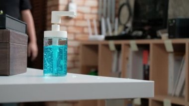 Yakın çekim: Sıradan bir adam, sağlık hijyeni için bir şişe alkol jeli, el dezenfektanı ve Coronavirus (Covid 19) gibi hastalık ve bakterileri önlemek için evde çalışırken bir şişe alkole bastırıyor..