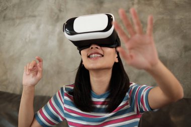 VR gözlüklü Asyalı kadın, 3 boyutlu sanal gerçeklik simülasyon oyunu izliyor. Etkileşimli eğlence teknolojisi aleti yenilikçidir. İnsanlar gelecekçi siber uzaya, modern yaşam tarzına giriyorlar..