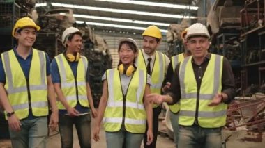 Çeşitli yarış işçileri ve fabrika mühendisleri tatilde makine yedek parça deposunda şakalaşarak eğleniyorlar. Tüm takım güvenlik üniforması ve endüstriyel kasklar giyiyor..