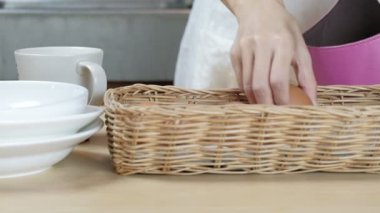 Yakın plan çekimde, kadın şef çantadan taze organik yumurtaları çıkarır ve kahvaltılık yemek, sağlıklı protein yiyecekler ama yüksek kalorili yemek olarak pişirmeden önce evin mutfağındaki ahşap masaya koyar.. 