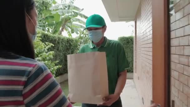 Yüzü Maskeli Yeşil Üniformalı Teslimatçı Asyalı Kadının Evine Paket Paketi — Stok video