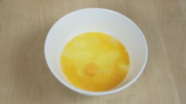 Yakın çekim ve yavaş çekim görüntülerinde kırık bir yumurta beyaz bir kaseye düşer ve evin mutfağındaki ahşap bir masada yemek hazırlar. Ev yapımı un unlu börek yemek sağlıklı bir kahvaltılık yemektir..
