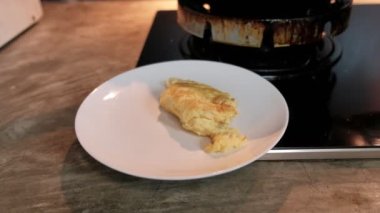 Şef, kahvaltı yemeği için boş beyaz tabakta spatula ile sıcak tavada ev mutfağındaki gaz sobasında omlet pişiriyor. Kızarmış yumurta yumurtaları yüksek protein ve lezzetli sağlıklı yiyecekler içerir..