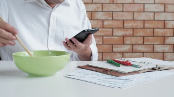 Rušný Mužský Pracovník Mobilním Telefonem Používá Hůlky Jíst Instantní Nudle — Stock video