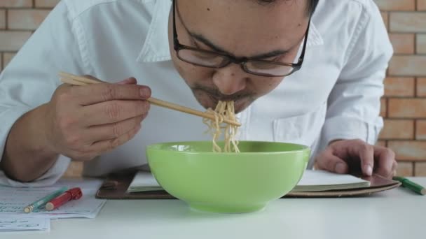 Asian Male Worker Reads Appointment Book While Eating Instant Noodles — Stock Video