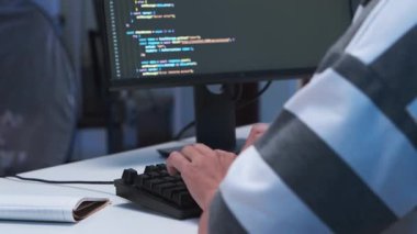 Bilgisayar klavyesiyle çalışan bilişim serbest programcısı ve teknoloji mühendisi, uygulama geliştirme için el yazması yazılım kodları ve oda içinde web sitesi ağ bilgileri.