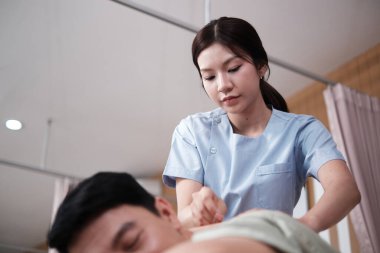 Asyalı kadın fizyoterapist, akupunkturlu erkek hastayı iyileştirir, ağrı kesici için el prosedürü, geleneksel doğu pasif tedavisi, hastane kliniğindeki sağlık bakım merkezlerinde tıbbi tedavi.