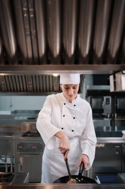 Beyaz önlüklü, beyaz önlüklü kadın şef restoran mutfağında pilav pişiriyor. Lezzetli mutfak yemekleri, malzeme hazırlama ve mutfak yemeklerinde profesyonel gurme becerileri var..