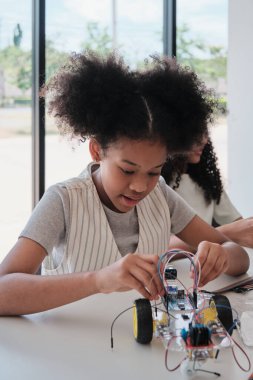Siyah öğrenci kız robotik mekanik tasarım ve elektrik deneyleri, fen mühendisliği sınıfında öğrenme dersi, yaratıcılık, ilkokul çocukları için teknoloji bilgisi.