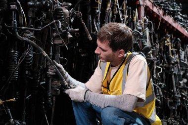 Genç beyaz erkek işçi, yığın deposunda yedek parça depolama, imalat fabrikasında işçi olarak çalışma ve dağıtım işi için endüstriyel mesleği kontrol ediyor..