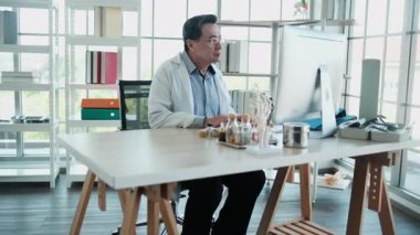 Profesyonel kıdemli Asyalı doktor işe odaklanır, hastanede bilgisayar kullanır, kayıt değerlendirmeleri, laboratuvar teşhisi araştırmaları ve ilaç reçetesi, uzman doktor mesleği.