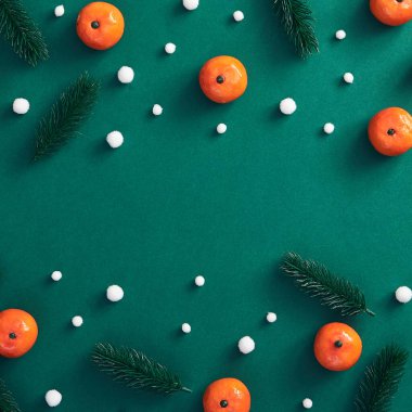 Noel asgari konsepti - ağaç dalı, kar yağışı ve koyu yeşil arka planda mandalinadan oluşan Noel kompozisyonu. Yeşil arka planda noel kartı. Koyu yeşil arka plan. Kış mevsimi.