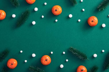 Noel asgari konsepti - ağaç dalı, kar yağışı ve koyu yeşil arka planda mandalinadan oluşan Noel kompozisyonu. Kutlama kartpostalı. Noel şablonu. Kış tatili dekorasyonu.