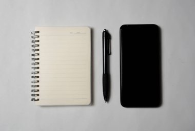 Yukarıdan bakıldığında bir kalem ve bir akıllı telefon olan bir defter var..