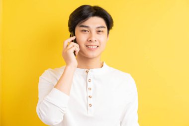 Asyalı adamın sarı arka planda fotoğrafı var.