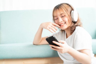 Genç kız telefonunu kullanarak kanepeye yaslandı.