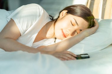 Güzel Asyalı kadın telefonunu yanına almış uyuyordu.