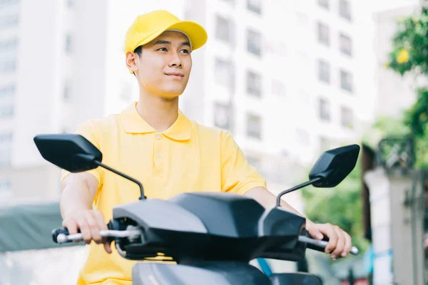 Asian delivery person is driving his motorcycle to deliver to customer