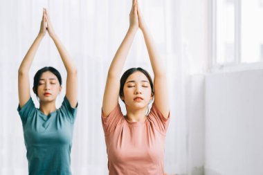 İki Asyalı kadın evde meditasyon yapıyor.