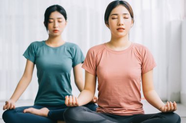 İki Asyalı kadın evde meditasyon yapıyor.