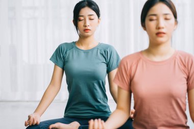 İki Asyalı kadın evde meditasyon yapıyor.