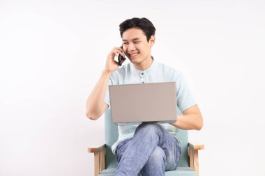 Bilgisayarlı yakışıklı adam kanepede oturmuş telefon dinliyor ve çalışıyor.