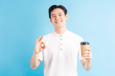 Elinde kağıt bardak tutan yakışıklı bir Asyalı çocuk resmi ve normal bir sembol.