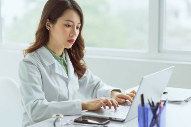 Ofiste bilgisayarla çalışan Asyalı kadın doktor.