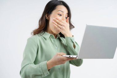 Güzel Asyalı iş kadınının portresi. Laptop ekranına şaşkın şaşkın bakıyor.