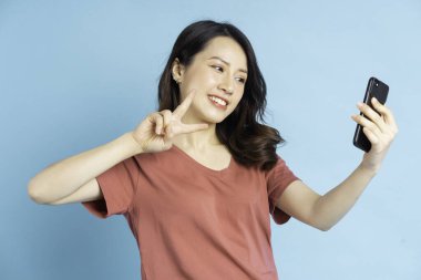 Asyalı kadın selfie çekmek için akıllı telefon kullanıyor.