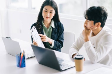 İki genç Asyalı işadamı yıl sonu projesini tartışıyorlar.