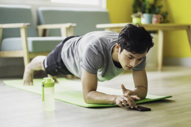 Asyalı adam evde egzersiz yapıyor.