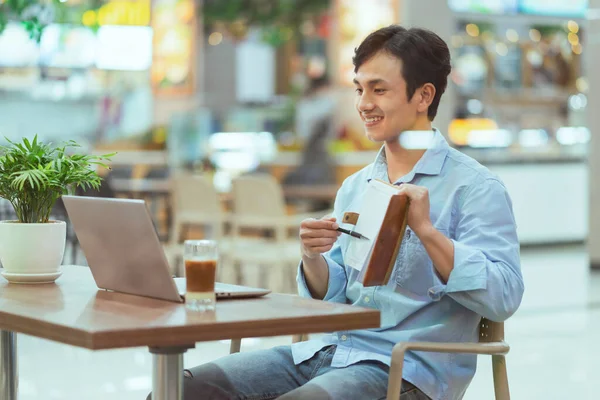 Asian man sitting working alone at a coffee shop