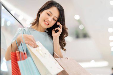 Genç kız alışveriş merkezinde telefonu kullanıyor.