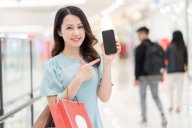 Alışveriş merkezindeki telefonu işaret eden genç kız.