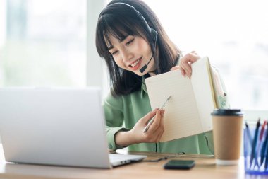 Güzel Asyalı müşteri hizmetleri görevlisi müşterileri arayıp ürün teklif ediyor.