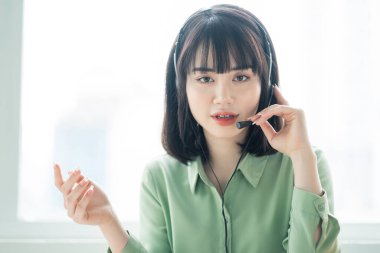 Güzel Asyalı müşteri hizmetleri görevlisi müşterileri arayıp ürün teklif ediyor.