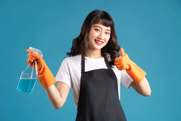 A photo of an Asian woman in an apron and gloves preparing for the cleaning job