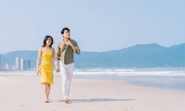 Genç Asyalı çift sahilde yaz tatilinin tadını çıkarıyor.