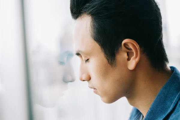 Sad Asian man by the window