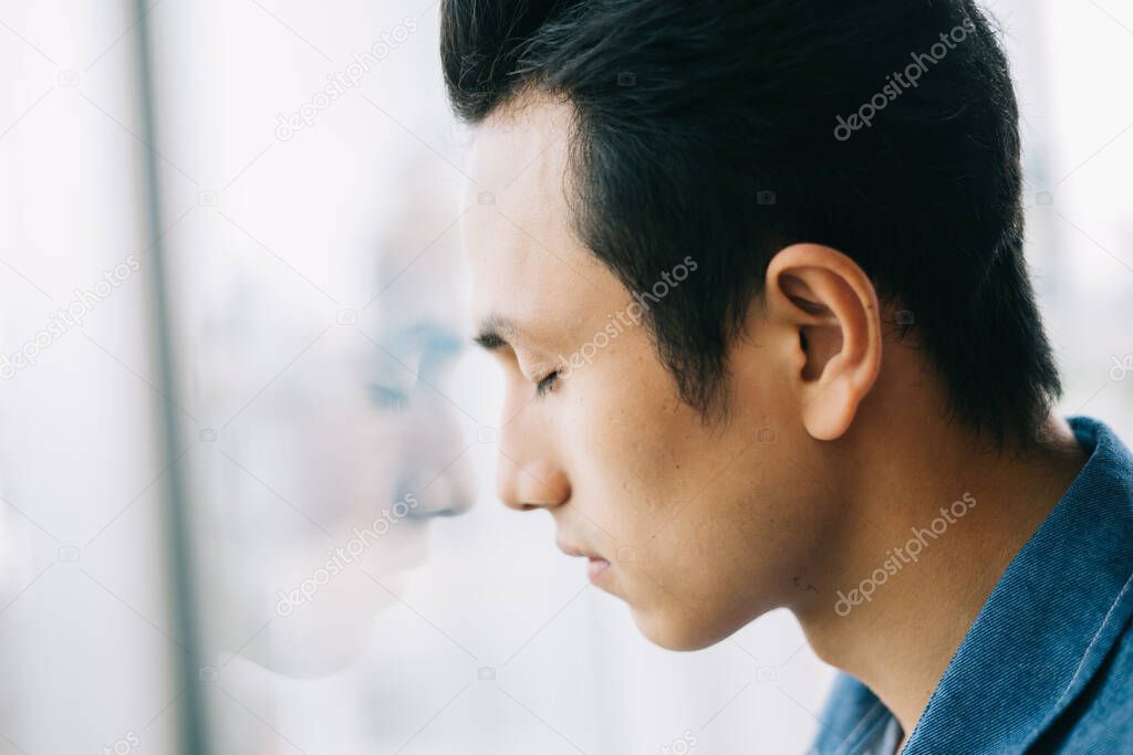 Sad Asian man by the window