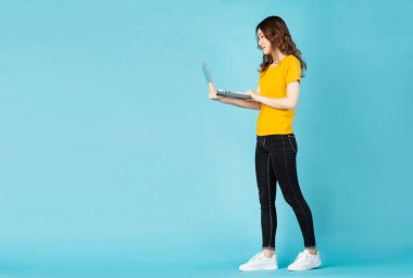 Arka planda dizüstü bilgisayar kullanan Asyalı genç bir kız.