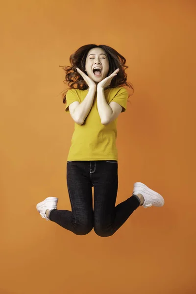 Giovane Ragazza Asiatica Saltando Sfondo Arancione — Foto Stock