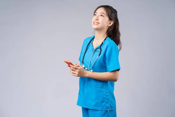 Joven Médico Asiático Con Smartphone Sobre Fondo Gris — Foto de Stock