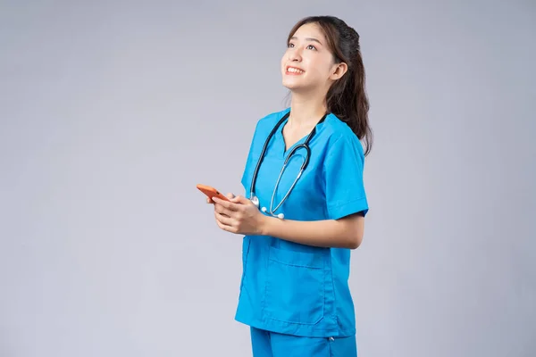 Joven Médico Asiático Con Smartphone Sobre Fondo Gris —  Fotos de Stock